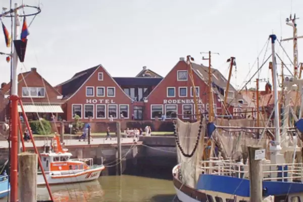 Im Vordergrund liegen einige Schiffe auf dem Wasser, dahinter erkennt man das Hotel Rodenbäck.