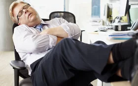 Ein Mann mit Narkolepsie schläft im Schreibtischstuhl.