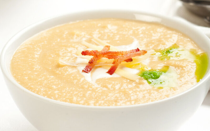 Apfel-Sellerie-Suppe mit Speck garniert.
