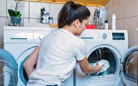 Eine Frau belädt eine Waschmaschine mit Wäsche.