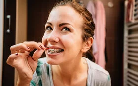 Ein Mädchen reinigt ihre Zahnspange mit einer Zahnzwischenraumbürste.