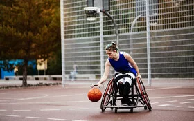 Eine Frau im Rollstuhl spielt Basketball.