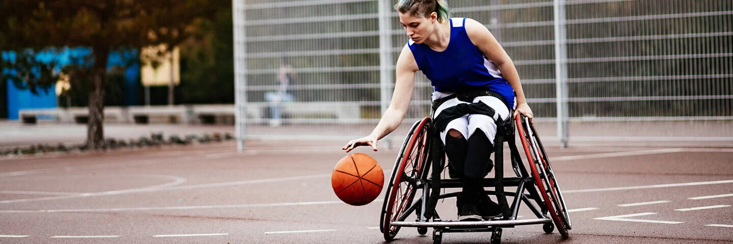 Eine Frau im Rollstuhl spielt Basketball.
