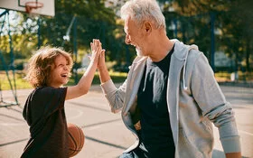 Ein Großvater spielt mit seinem Enkel Basketball und schlägt ab.