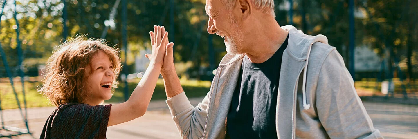 Ein Großvater spielt mit seinem Enkel Basketball und schlägt ab.