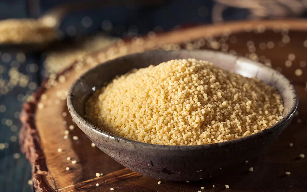 Eine Schüssel mit Couscous steht auf einem Holzbrett.