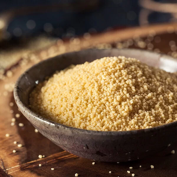 Eine Schüssel mit Couscous steht auf einem Holzbrett.