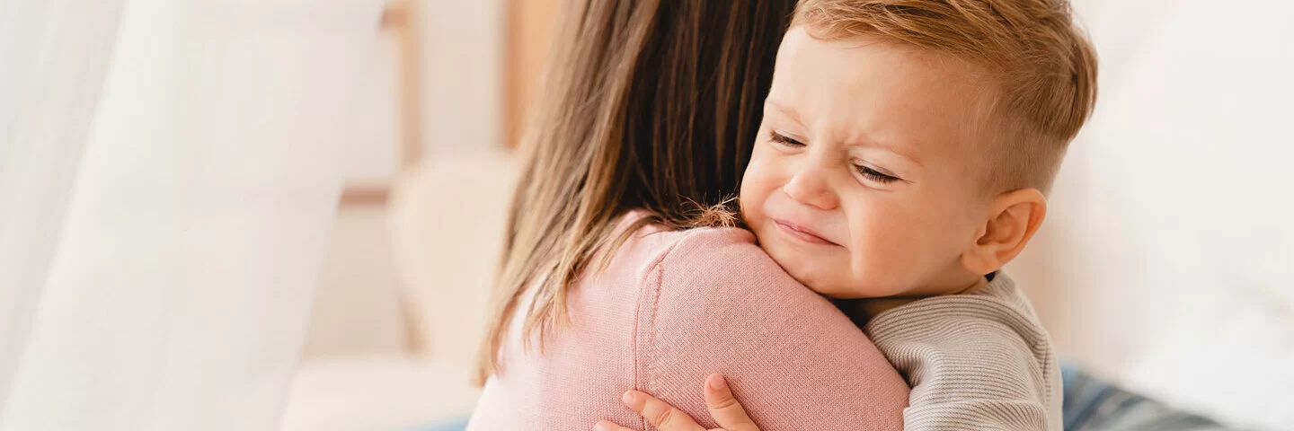 Eine Frau hält ein Baby, das unter Durchfall leidet, auf dem Arm.