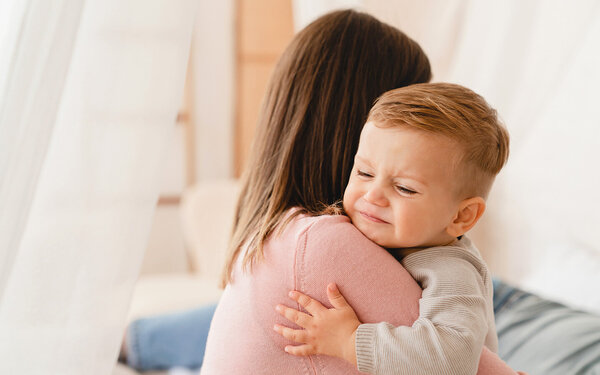 Eine Frau hält ein Baby, das unter Durchfall leidet, auf dem Arm.