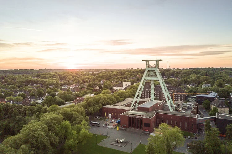 Luftaufnahme von Bochum mit Förderturm des Bergbaumuseums im Sonnenuntergang.