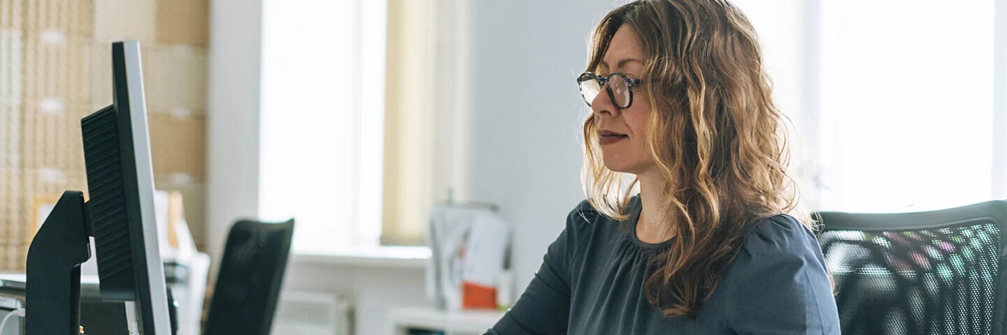 Eine Frau arbeitet am Schreibtisch und leidet unter Bewegungsmangel.