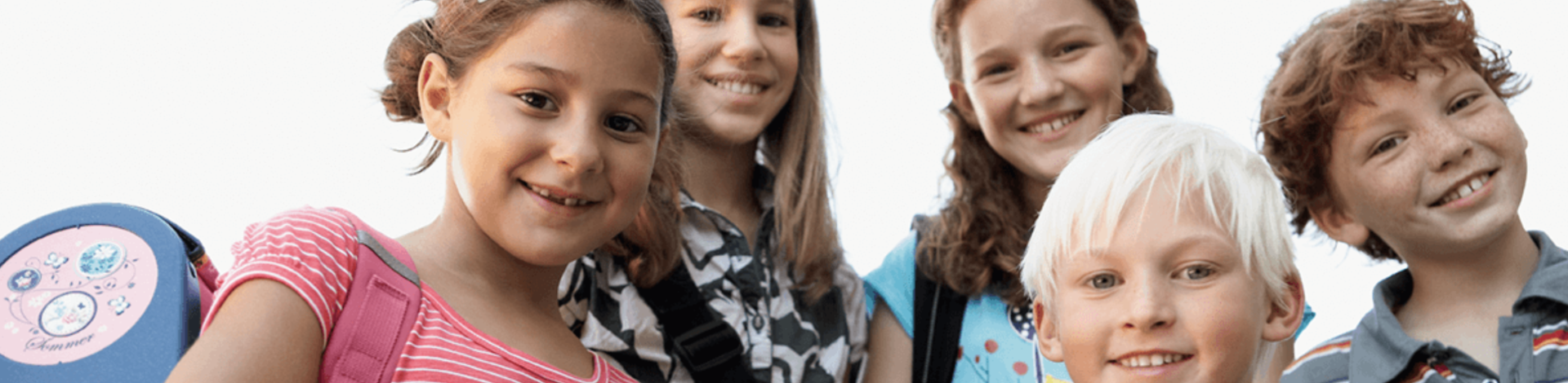 Drei Mädchen und zwei Jungs grinsen in die Kamera. Sie sind Grundschüler.