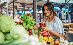 Eine Frau greift auf dem Markt nach frischen Radieschen.