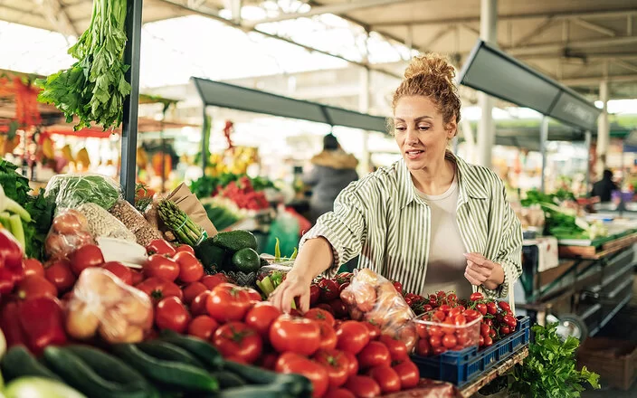 Eine Frau greift auf dem Markt nach frischen Tomaten.