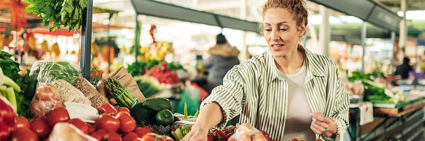 Eine Frau greift auf dem Markt nach frischen Tomaten.