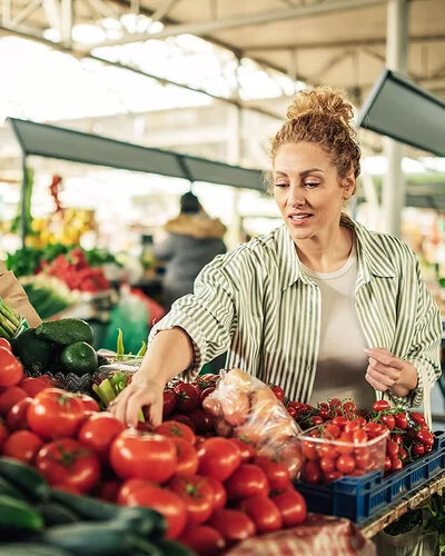 Eine Frau greift auf dem Markt nach frischen Tomaten.