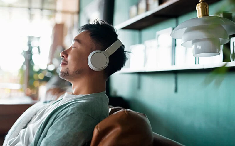 Ein Mann mit Synästhesie hört über Kopfhörer Musik.