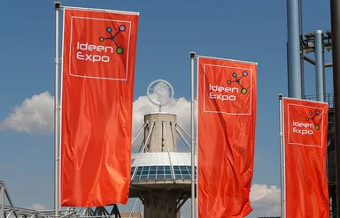 Drei rote Flaggen mit dem Logo der Ideenexpo wehen vor dem Eingang der Hannover Messe.