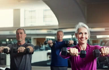 Ältere Menschen trainieren mit Kurzhanteln in einem Fitnessstudio.
