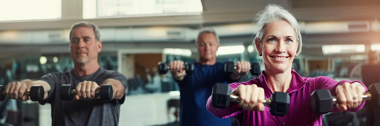 Ältere Menschen trainieren mit Kurzhanteln in einem Fitnessstudio.