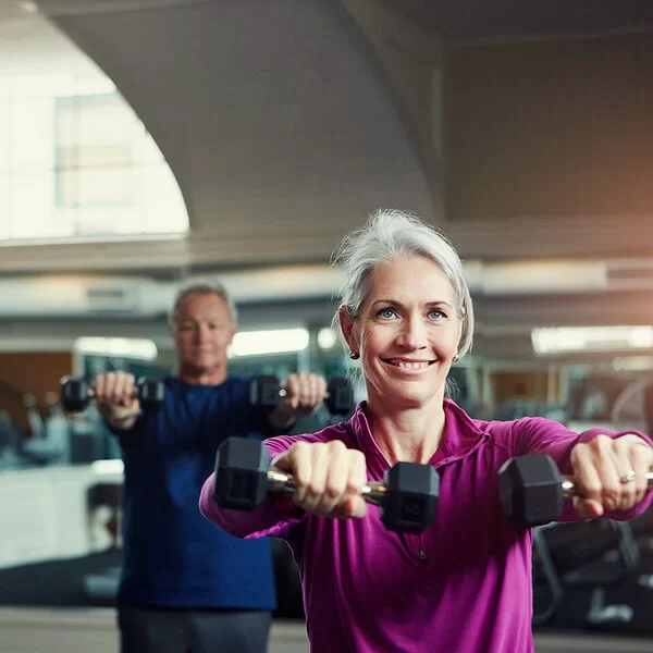 Ältere Menschen trainieren mit Kurzhanteln in einem Fitnessstudio.