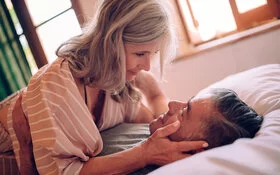 Ein älteres Ehepaar küsst sich im Bett, denn auch Menschen mit einer Herzkrankheit müssen nicht auf Sexualität verzichten.