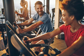 Mehrere Personen trainieren in einem Fitnessstudio.