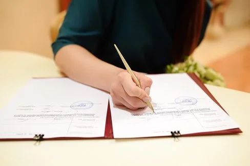 Eine nicht erkennbare Person unterschreibt ein Dokument.