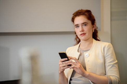 Eine Frau hat ein Smartphone in der Hand. Wie hoch der Krankenkassenbeitrag für Angestellte ist, kann sie online recherchieren.