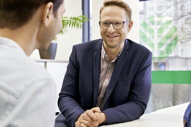 Ein Berater ist im Gespräch mit einem jungen Paar.