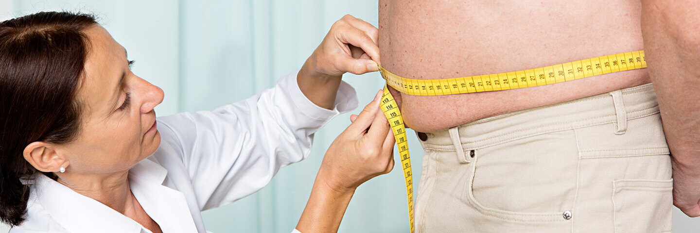 Eine Ärztin misst bei einem übergewichtigen Patienten den erhöhten Taillenumfang, der ein Symptom des metabolischen Symptoms sein kann.