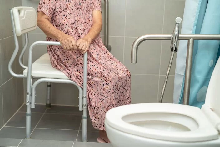Eine Frau sitzt in der Dusche auf einem Duschstuhl.