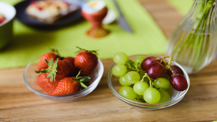 Erdbeeren und Trauben in einer Schale auf einem Frühstückstisch