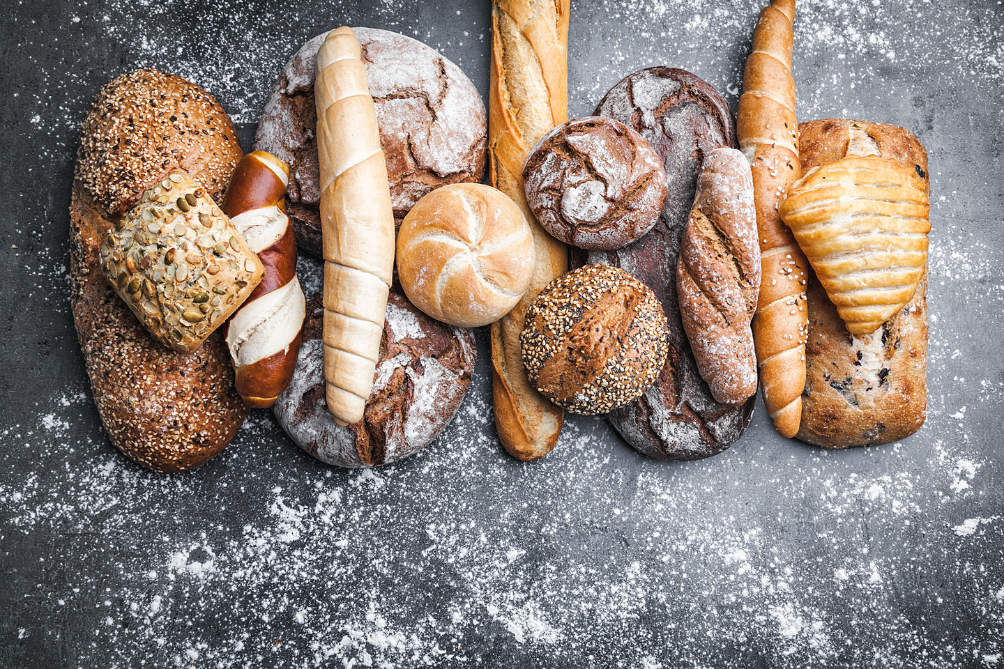 Auf einem Tisch liegen unterschiedliche Brotlaibe, Brötchen und andere Backwaren.