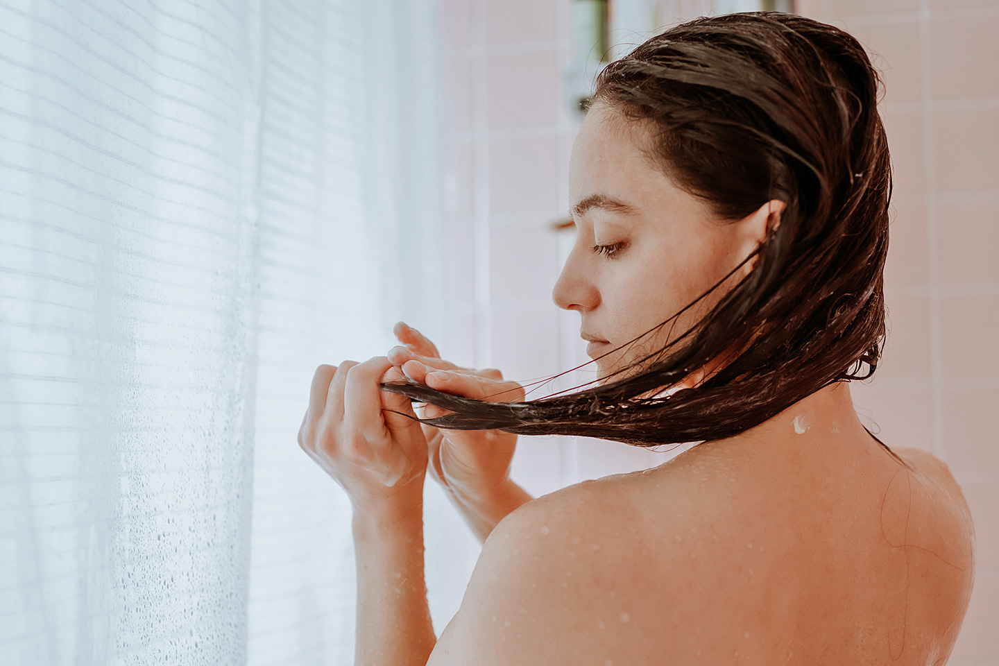 Eine Frau wäscht sich die Haare nur mit Wasser ohne Shampoo.