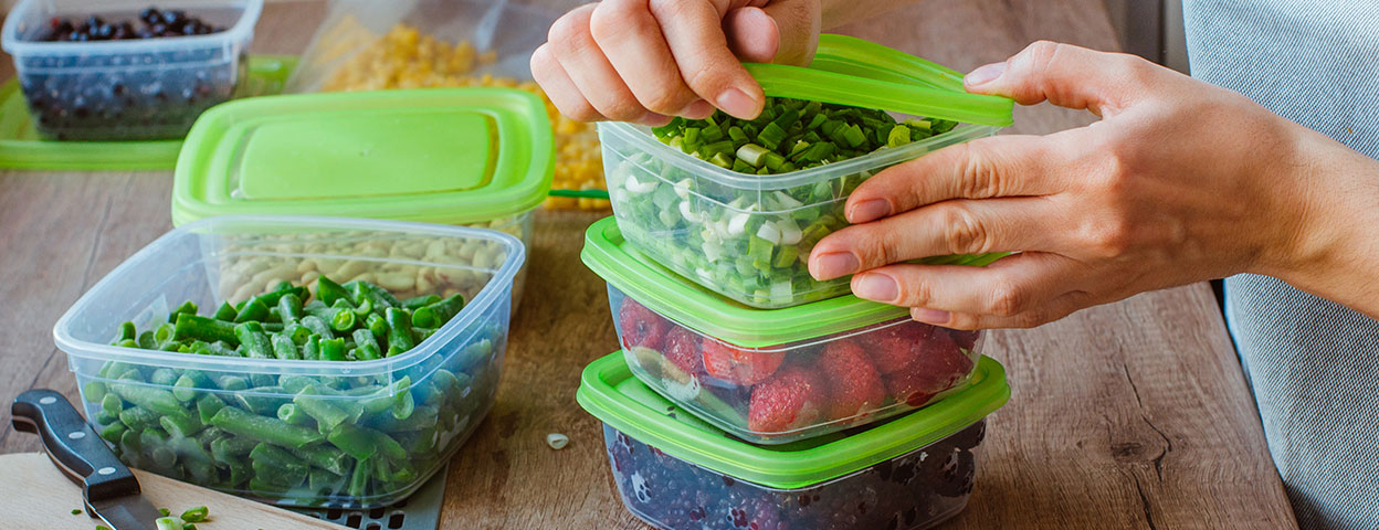 Eine Frau packt Lebensmittel zum Einfrieren in Plastikdosen