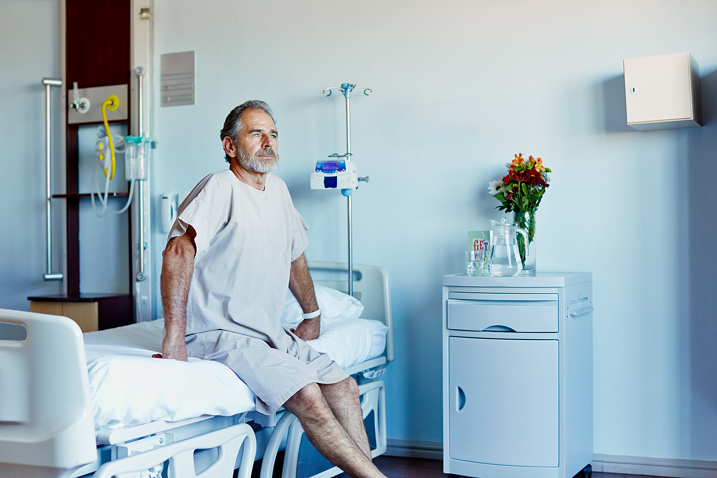 Ein Mann sitzt auf einem Krankenhausbett und denkt über multiresistente Keime nach.