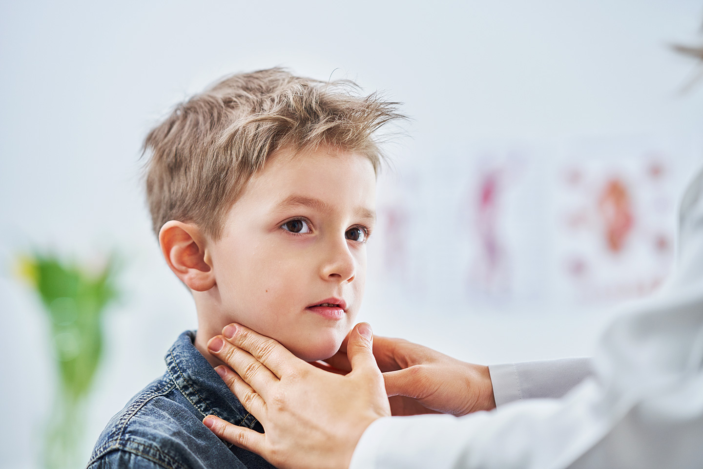 Eine Kinderärztin tastet den Hals eines kleinen Jungen nach Anzeichen von Mumps ab.