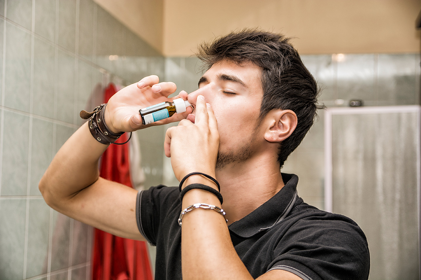 Junger Mann benutzt Nasenspray, weil er unter einer Nasenspraysucht leidet.
