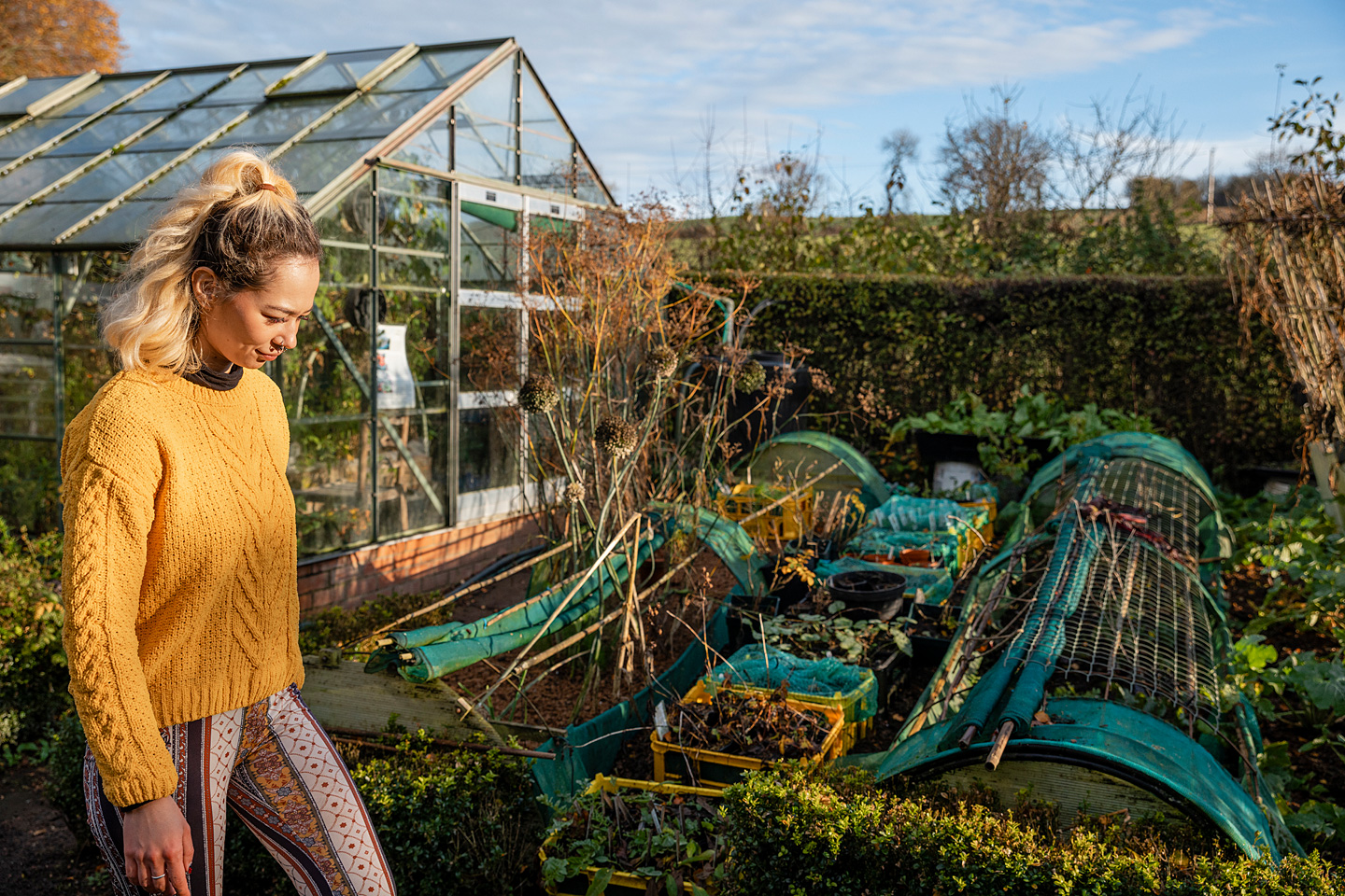 Frau geht durch ihren Schrebergarten, der nach dem Prinzip der Permakultur angelegt wurde.