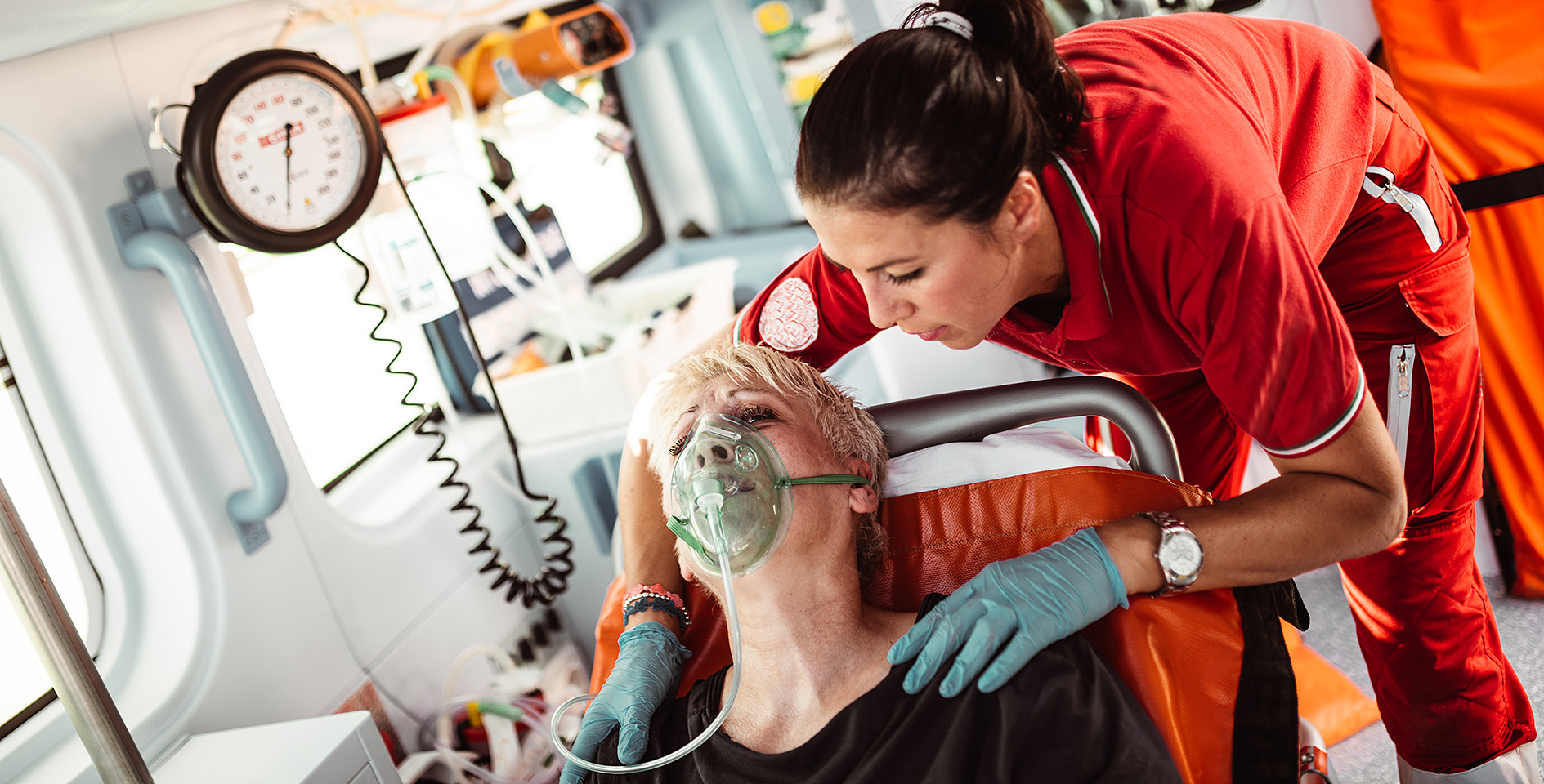 Eine Sanitäterin kümmert sich im Krankenwagen um eine Frau, die eine Atemmaske trägt.