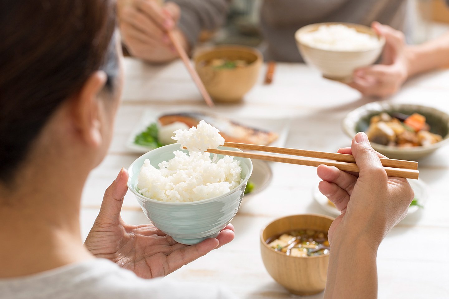 Resteverwertung von Reis: Eine Frau sitzt am Küchentisch und isst den Reis vom Vortag.