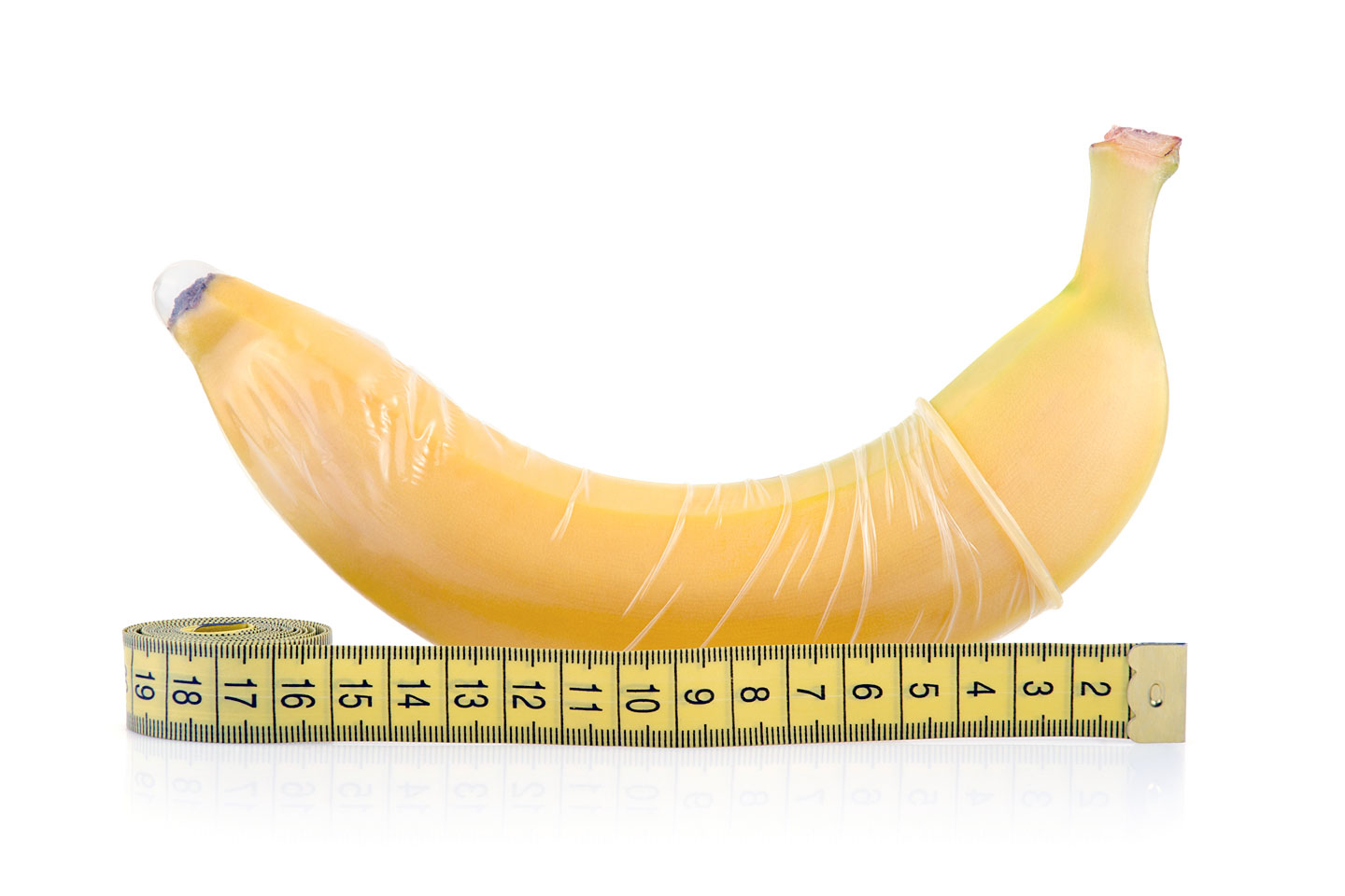 Banane mit übergezogenem Kondom neben einem Maßband