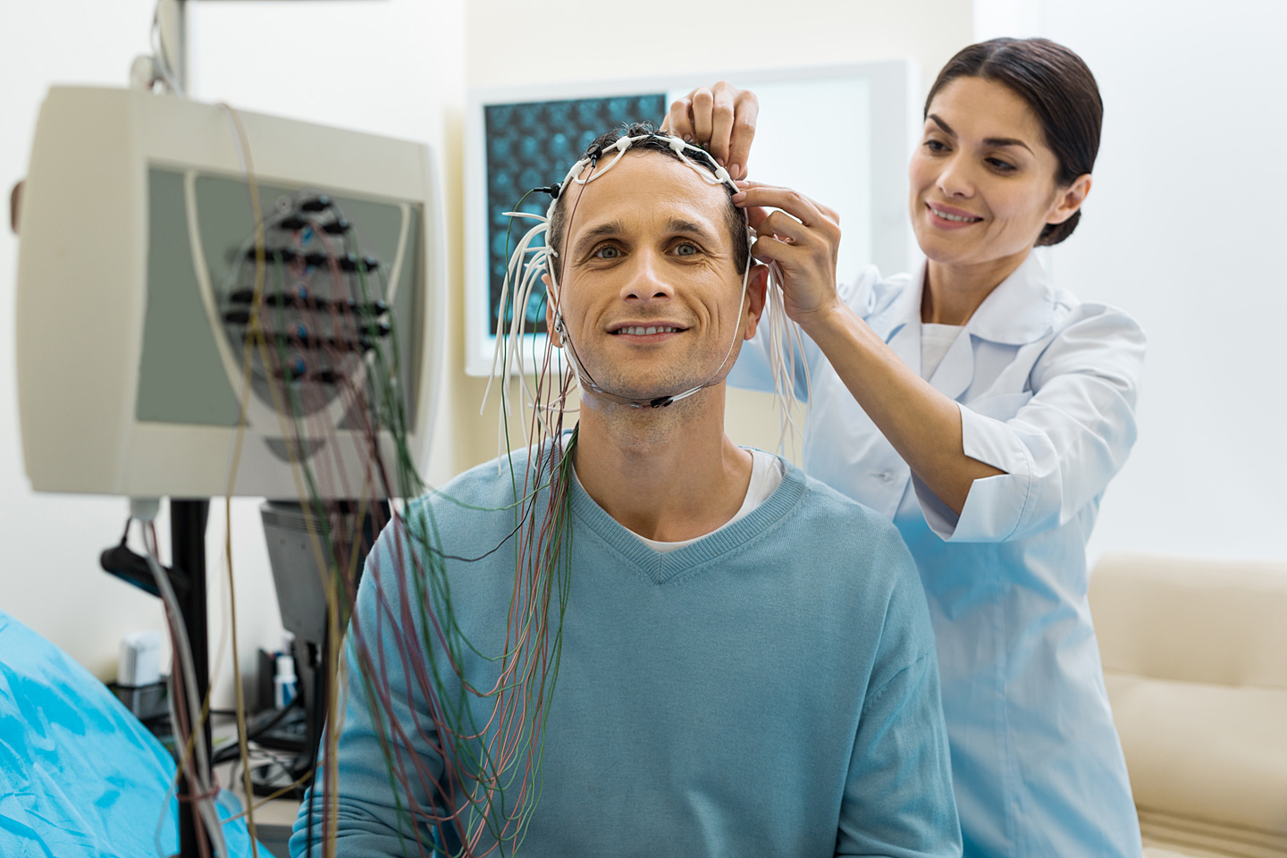 Eine Ärztin des Schlaflabors befestigt Elektroden am Kopf eines Patienten.