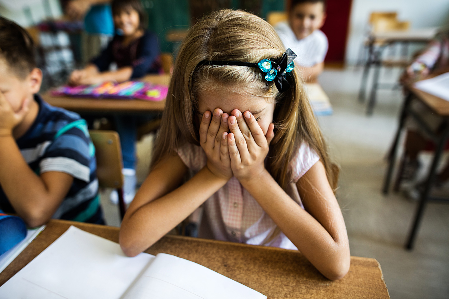 Ein Mädchen, welches Schulstress hat, hält sich die Hände an den Kopf.