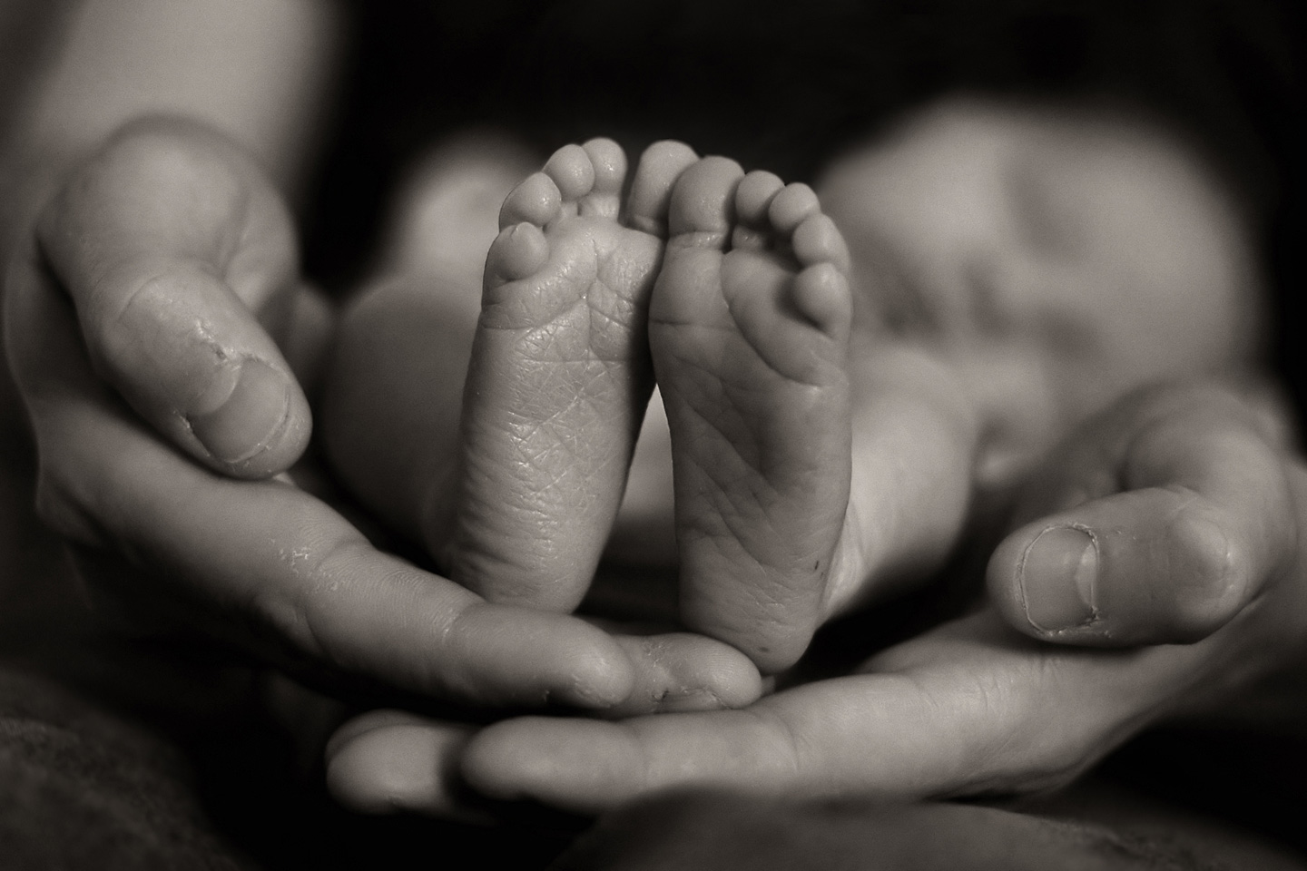 Die Hände der Mutter halten die Füße ihres Sternenkindes.