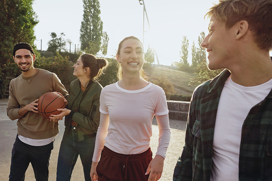 Vier junge Menschen stehen zusammen auf einem Basketballplatz.