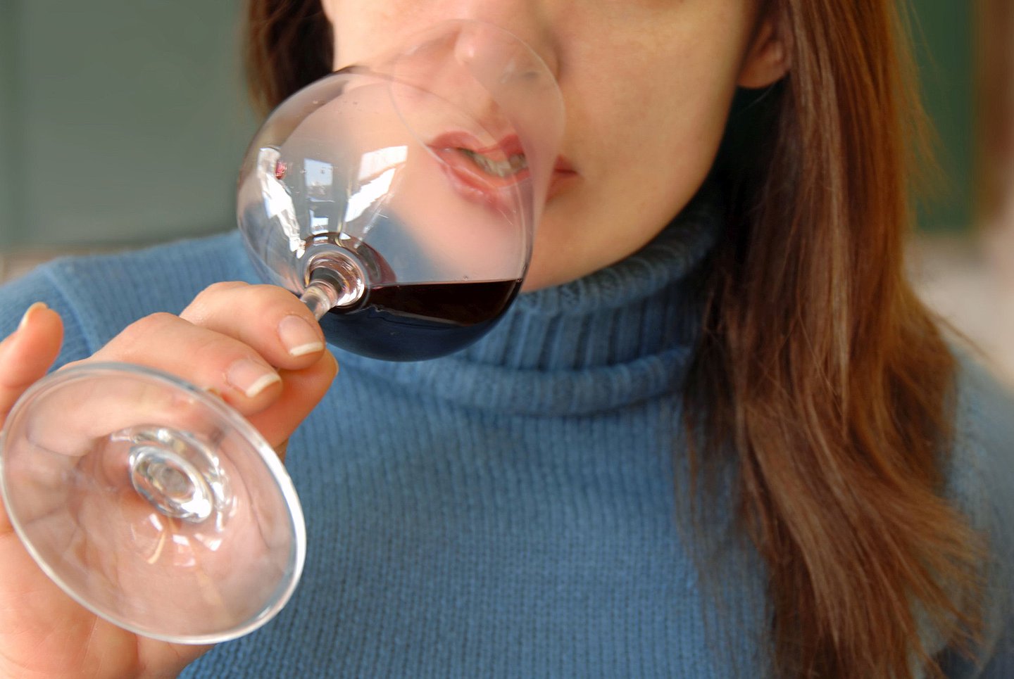 Foto einer Frau, die ein Glas Rotwein zum Mund führt und es austrinken will.
