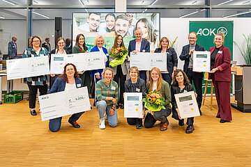 Das Foto zeigt die Preistr&auml;ger des GesundMacher Awards. Reihe vorne (v.l.n.r.): Verena Neubauer (Universit&auml;tsklinikum Erlangen), Laura Dahlmeier, Elke Schmidt und Bianca Adler (Universit&auml;tsklinikum Erlangen), Ulrike N&ouml;th (Gesundheitsnetz QuE) Reihe hinten (v.l.n.r.): Katharina Ehinger und Jasmin Hildner (Diakonisches Werk Coburg), Alina Wimmer und Cornelia Uschold (Constantia Pirk), Julia Oelmayer (Gesundheitsnetz QuE), Horst Leitner (Direktor AOK N&uuml;rnberg), Annette Lutz (Bereichsleitung Gesundheitsf&ouml;rderung AOK Bayern), Stephan Abele (Vorstandsvorsitzender der AOK Bayern), Christina Heinemann (Universit&auml;tsklinikum Erlangen)