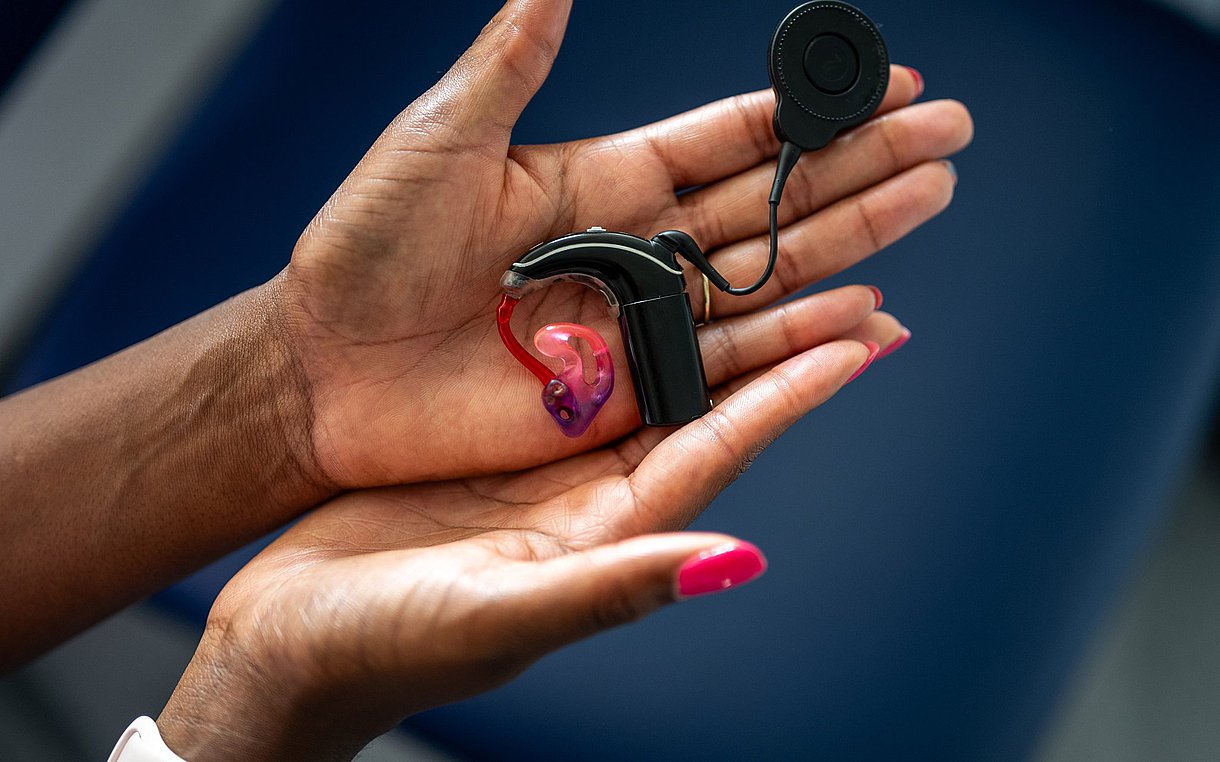 Foto von zwei Händen, die ein Cochlea-Implantat halten